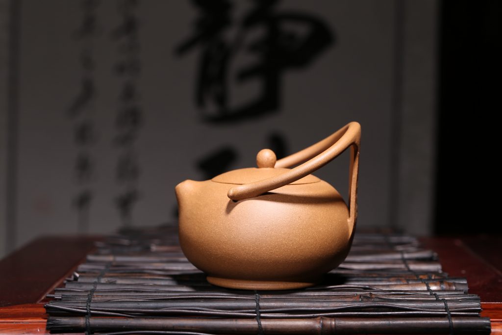 Tan clay Yixing teapot sitting on a textured mat