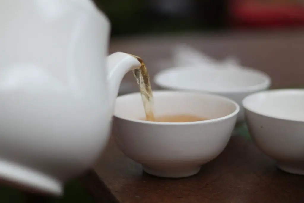 Serving freshly brewed tea with a white tea kettle