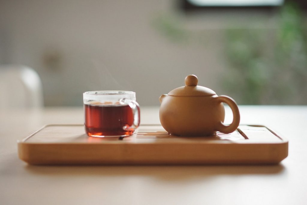 a cup of pu erh tea beside a brown ceramic pot