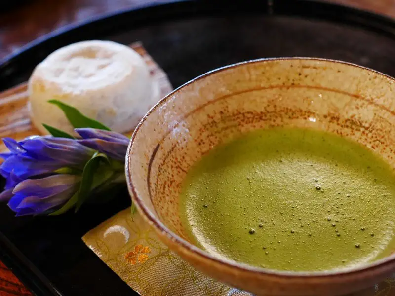 A cup of matcha tea paired with a plate of dessert