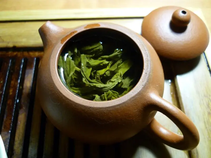 A teapot full green tea leaves