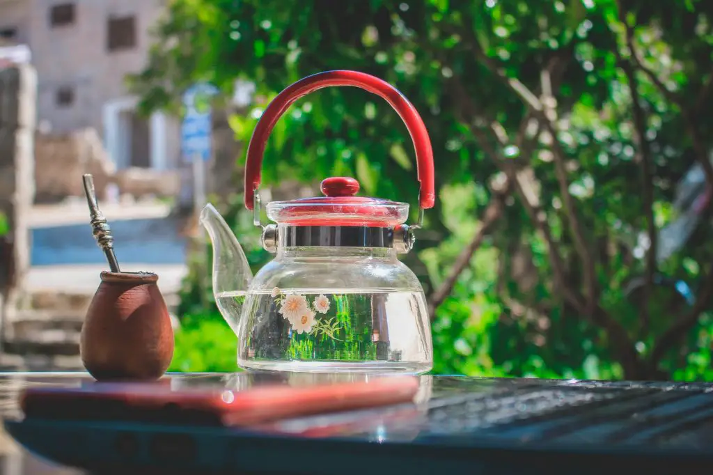 Glass teapot beside a clay jar