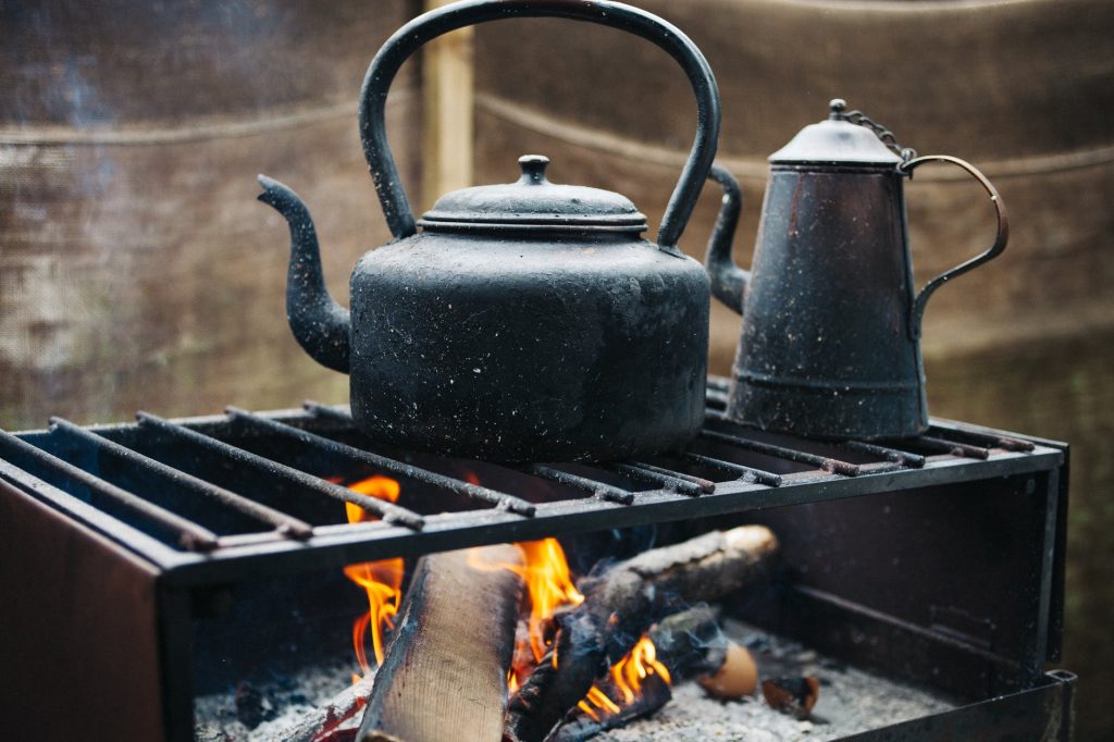 Boiling water with black cast iron kettle on a grill