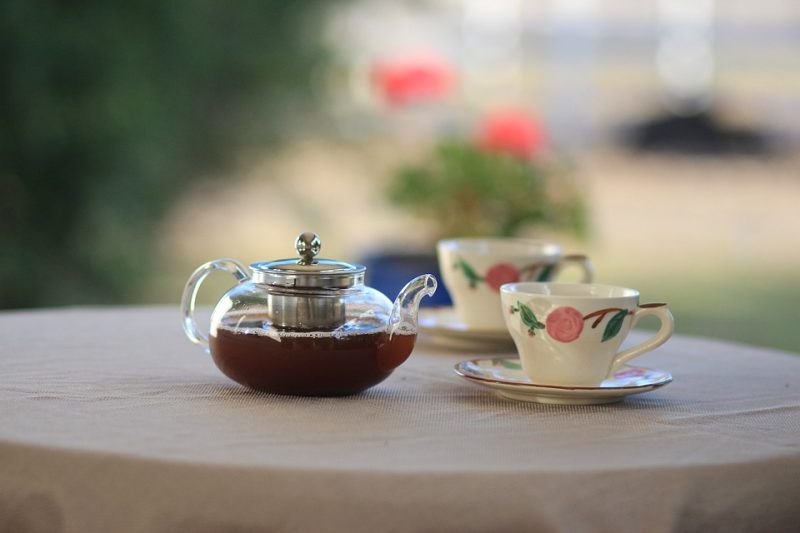 A teapot with black tea and two teacups on a table