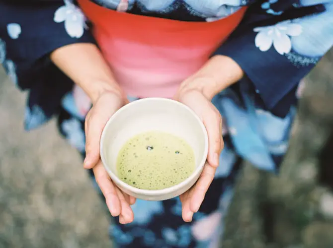A person holding a cup of matcha tea