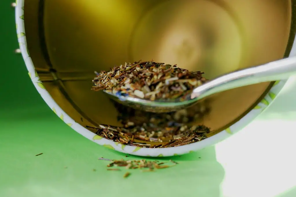 A tablespoon of tisane tea taken from a tea container