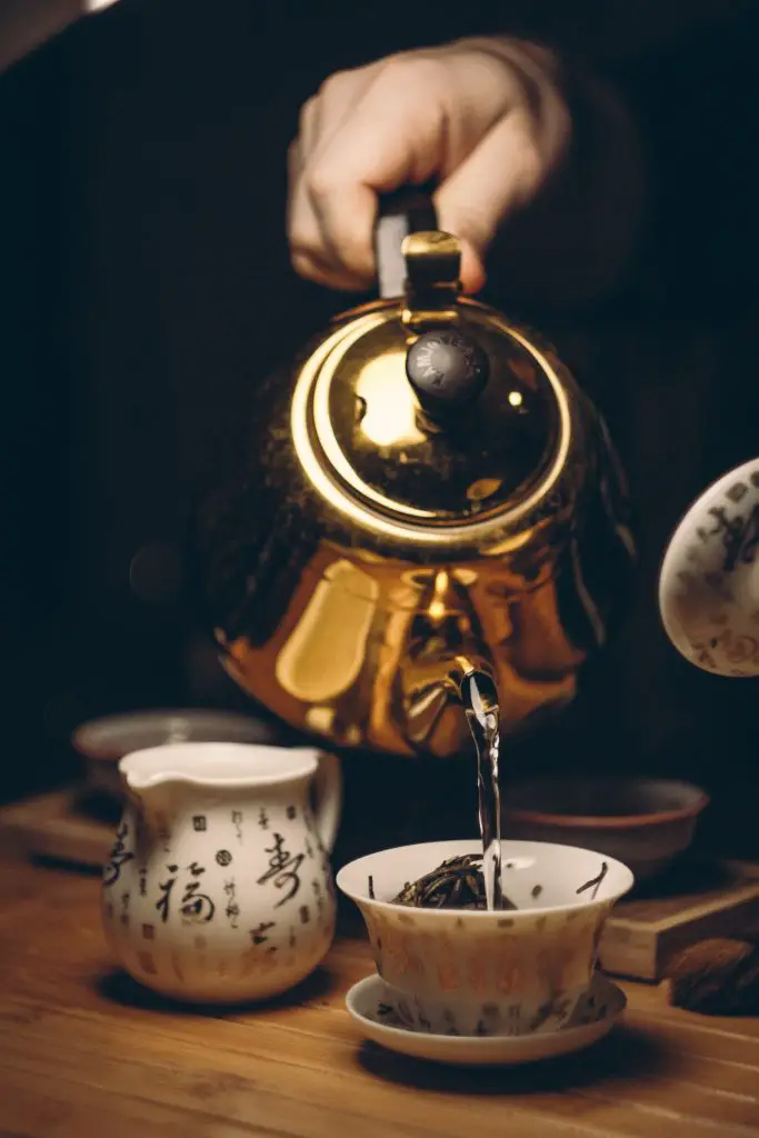 Hot water being poured over a bowl of loose tea leaves