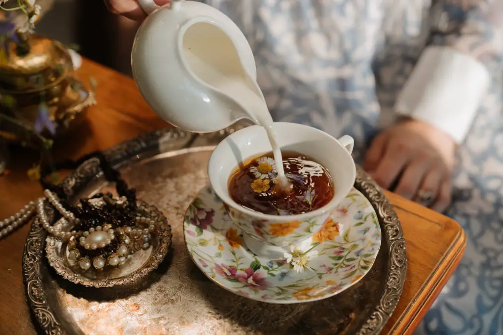 Person pouring milk over a cup of tea