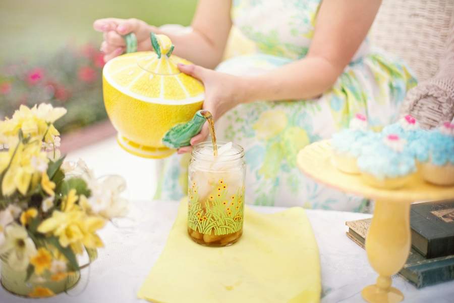Woman pouring tea on a drinking glass with ice cubes