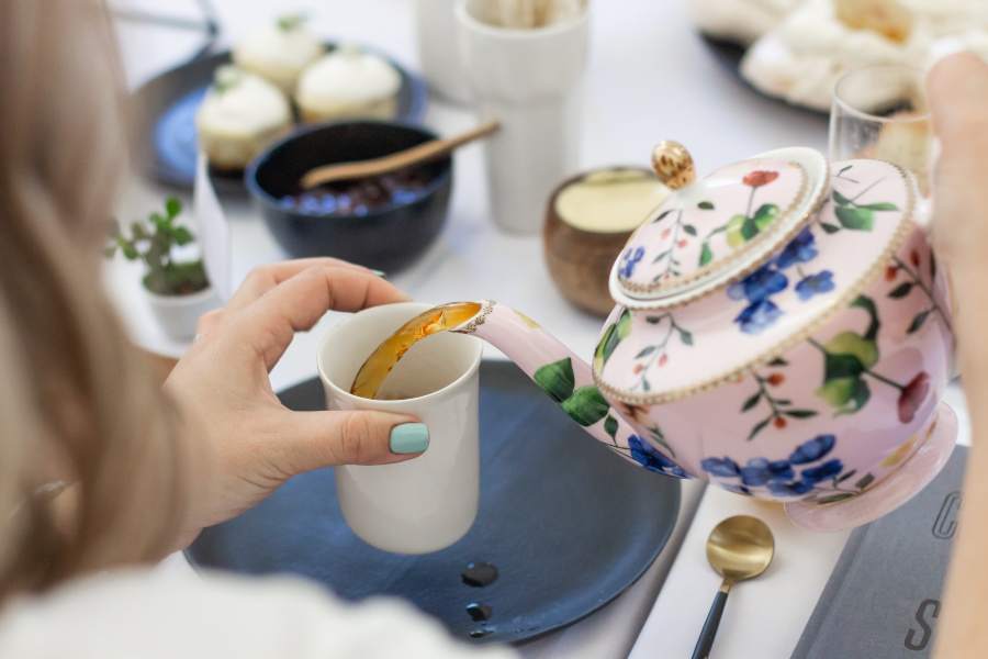 A woman pouring tea into a white cup