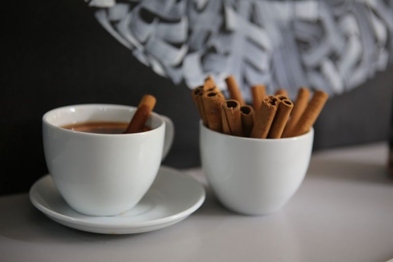 A cup of chai tea beside a bowl of cinnamon sticks