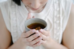 Woman drinking tea from a gray cup