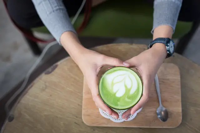 Picture of a woman holding a cup of matcha latte